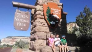 Kids sitting in front of the sign at zion national park