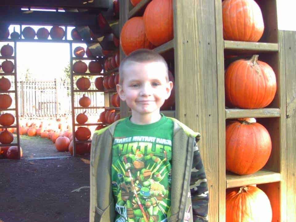 Kid standing next to pumpkins