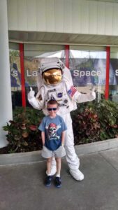 Young travelers posing with an astronaut at kennedy space center near orlando.