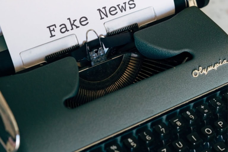 Close-up of a typewriter with a paper showing the text "fake news" in typed font, reminding us to go to the media with your iep issues for accurate representation and awareness.