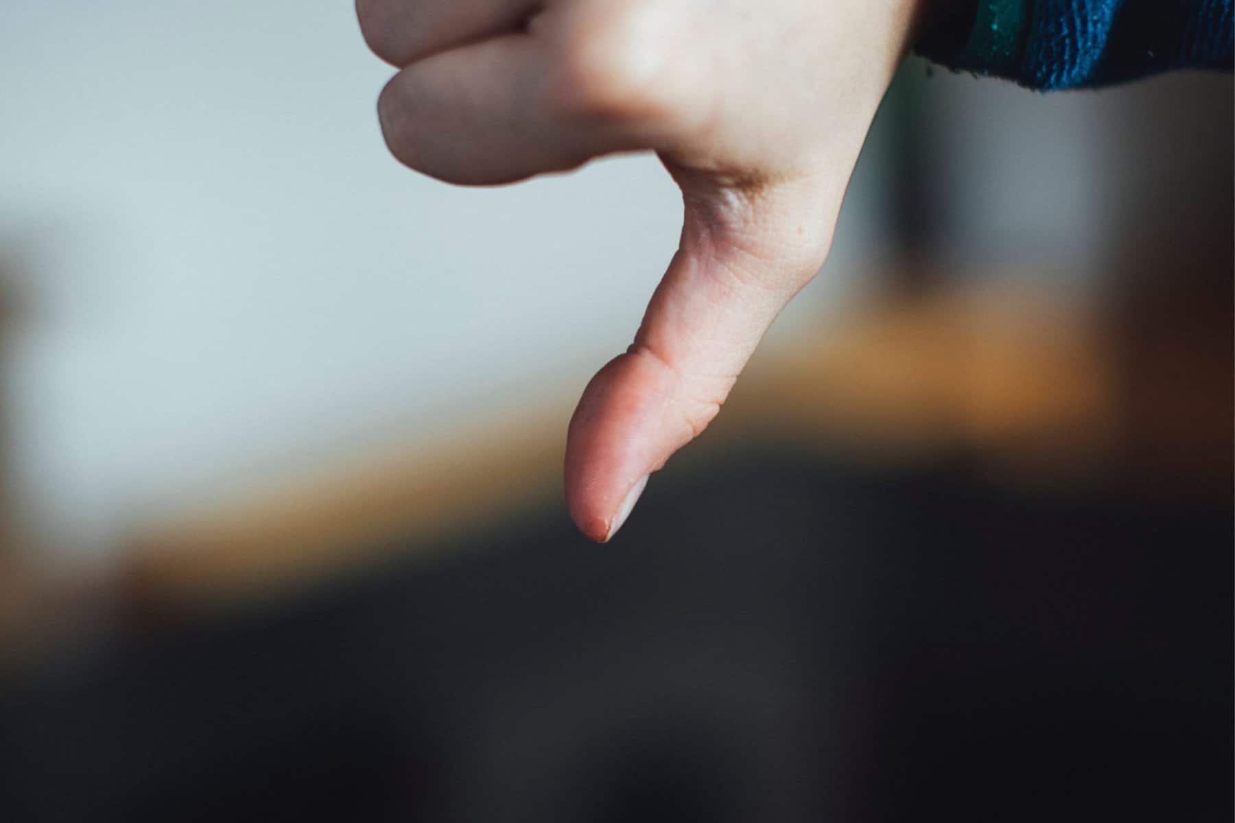 A close-up of a person's hand with their thumb pointing downwards to refuse special education services.