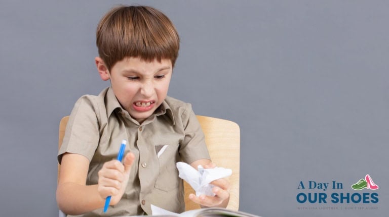 A young boy sits on a chair, looking frustrated as he crumples a piece of paper with one hand and holds a pen in the other—reflecting when an iep behavior plan is not working. The logo "a day in our shoes" is visible.