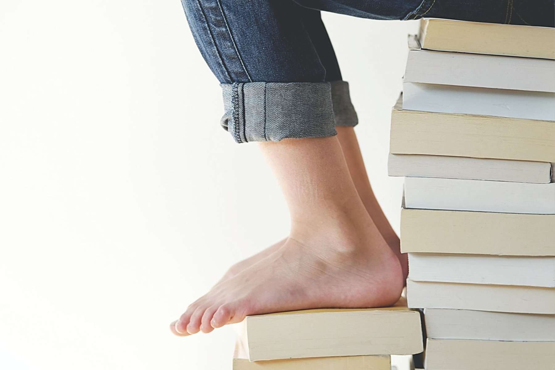 A woman's feet on top of a stack of books, symbolizing the steps she's taking to overcome dyslexia through her iep.