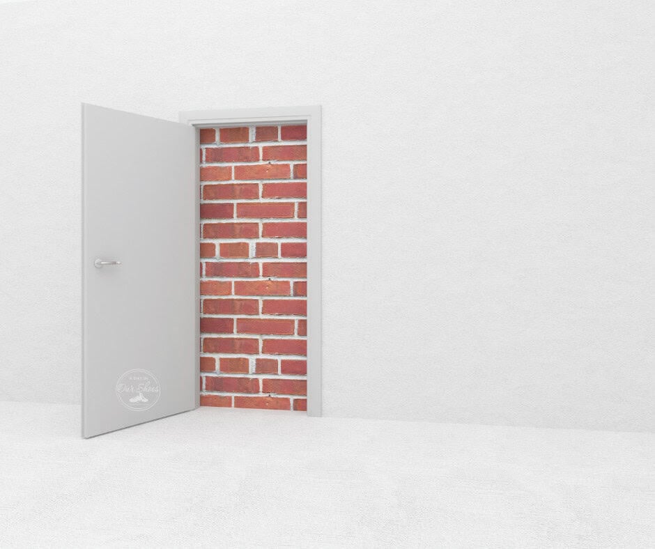 8 examples of how the special education system is rigged against parents. 1 An open door reveals a brick wall in a white room, symbolizing the challenges parents face when navigating a special education system stacked against them.