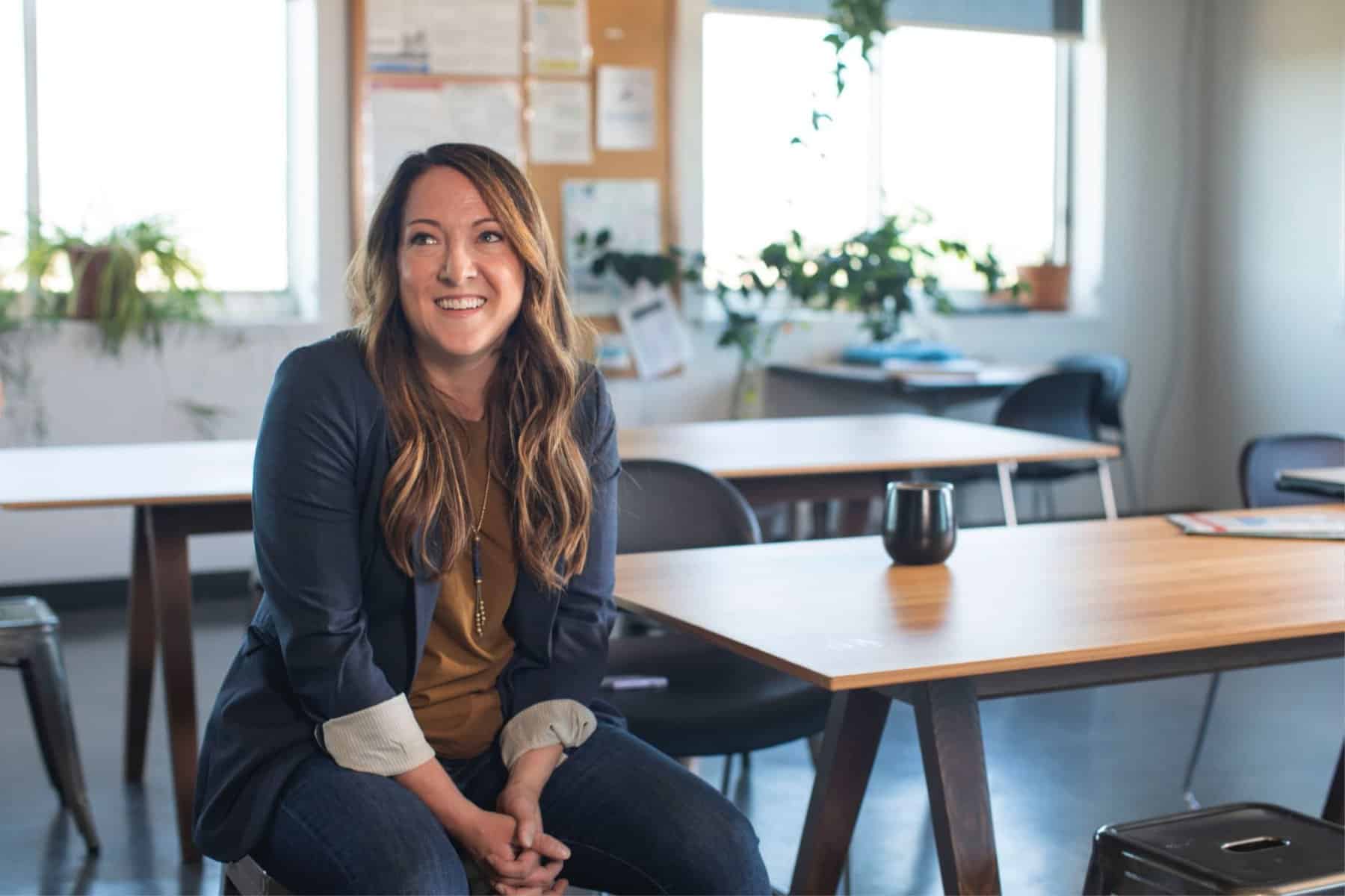 A woman sitting on a desk in an empty classroom contemplates how much special education advocates cost.