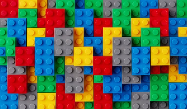An assortment of colorful plastic building blocks, including red, yellow, blue, green, and gray pieces, stacked in a random overlapping pattern—perfect for following along with your lego instructions.