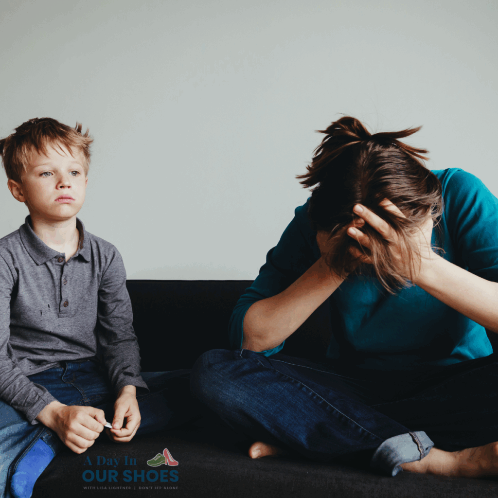 A young boy, recently suspended from school, sits on a couch next to an adult who is sitting with their head in their hands, appearing distressed.