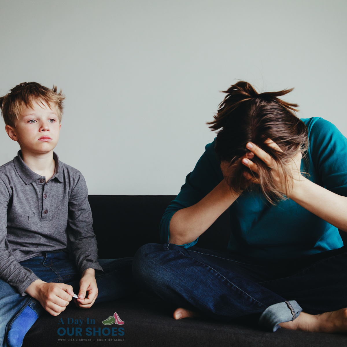 A young boy, recently suspended from school, sits on a couch next to an adult who is sitting with their head in their hands, appearing distressed.