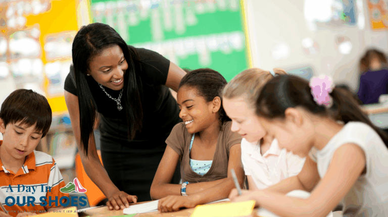 A teacher stands by four children, including a 2e student, sitting at a table in a classroom, smiling as the students work together on an assignment.