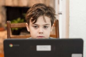 A young boy with a shortened day iep focusing intently on a laptop screen.