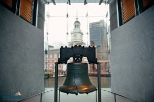The liberty bell is displayed indoors with independence hall visible through the glass window in the background, making it a must-see stop on any sensory friendly philadelphia itinerary.