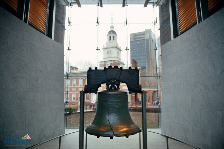 The liberty bell is displayed indoors with independence hall visible through the glass window in the background, making it a must-see stop on any sensory friendly philadelphia itinerary.