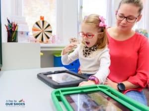 A young student and her slp work on her assistive technology goals with an aac device