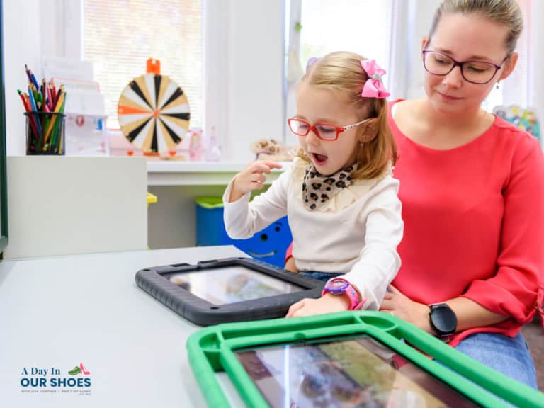 A young student and her slp work on her assistive technology goals with an aac device