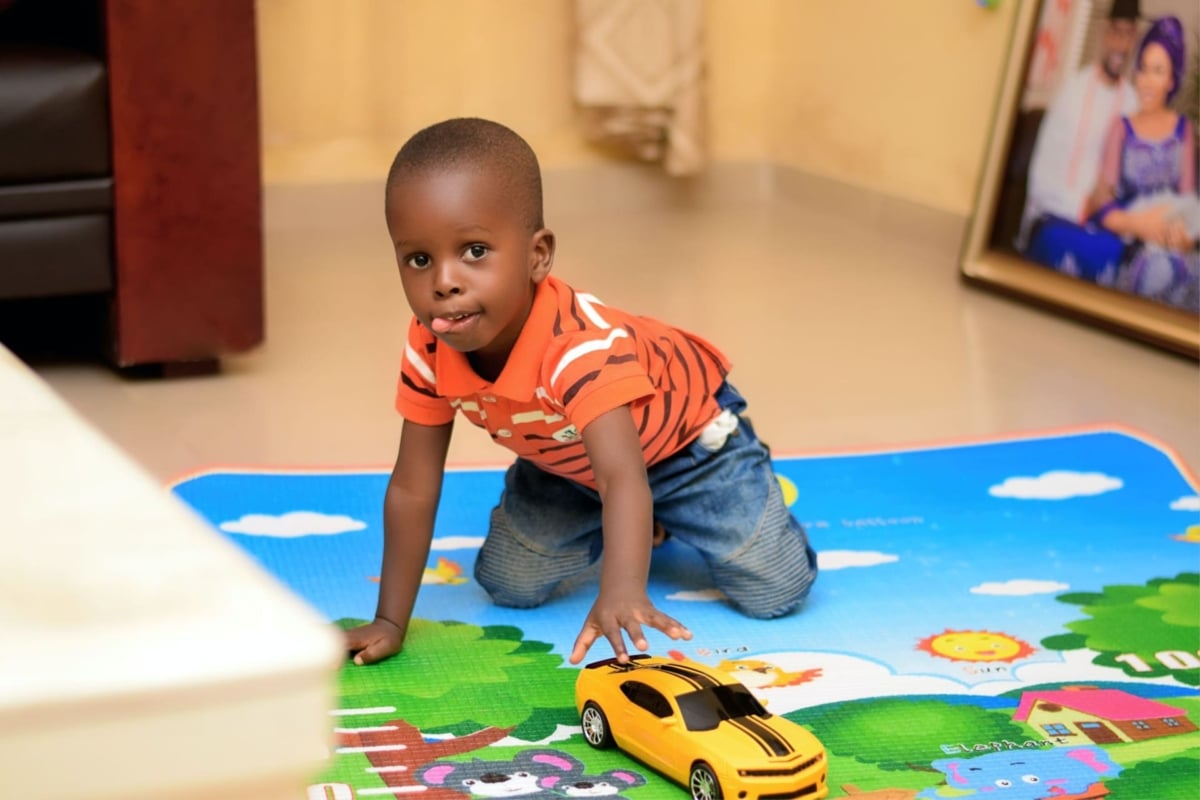A young boy plays with a toy car on a play mat in kindergarten.