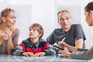 Parents and school student sitting in an iep meeting reviewing the graduation decision