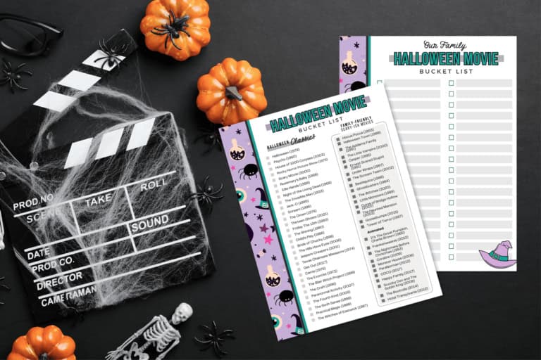 Flat lay of halloween-themed items: a movie clapperboard with spider webs, small pumpkins, fake spiders, a skeleton, and two "halloween movie bucket list" printables—perfect essentials for curating your ultimate halloween movies list—arranged on a dark surface.
