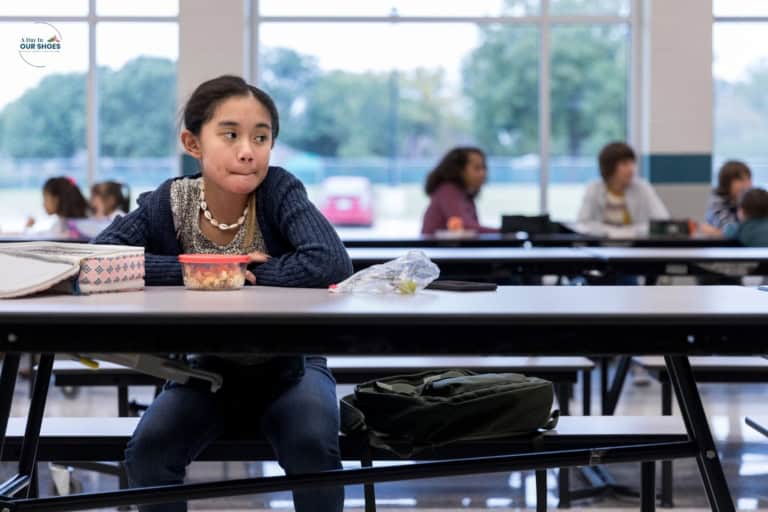 Tween girl sitting alone in the cafeteria because she struggles to make friends