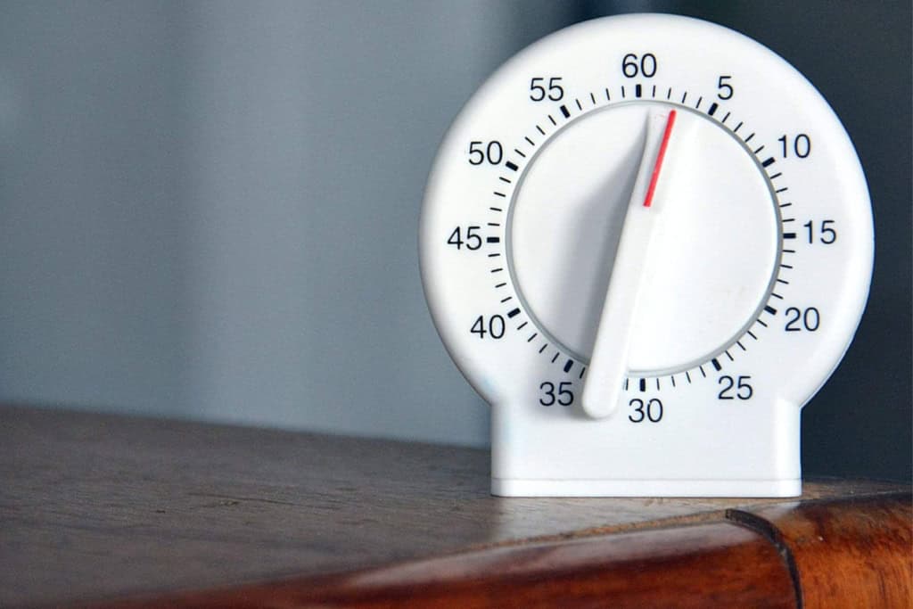 White visual timer showing 1 minute on a wooden surface.
