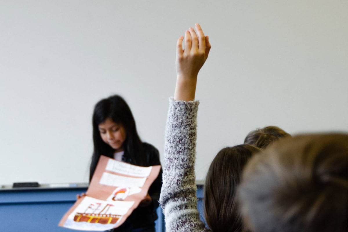 What is social emotional learning? A guide for parents 1 A group of students participating in social emotional learning activities, with their parents acting as guides, while raising their hands in a classroom.
