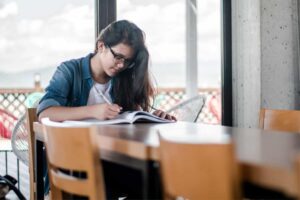 A girl, engaging in study skills, sits at a table intently reading a book.