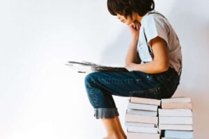 A person engaging in reading interventions while sitting on a stack of books.