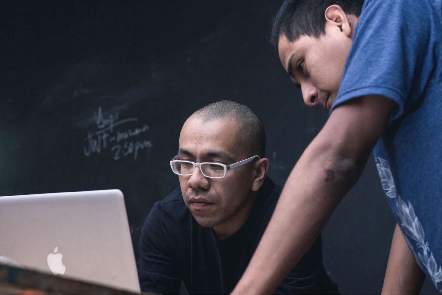 Two men working on a laptop in front of a blackboard, exploring how to teach executive functioning skills.