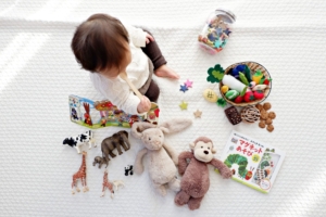 A baby is engaged in pretend play with stuffed animals on a bed, fostering their imagination and creativity.