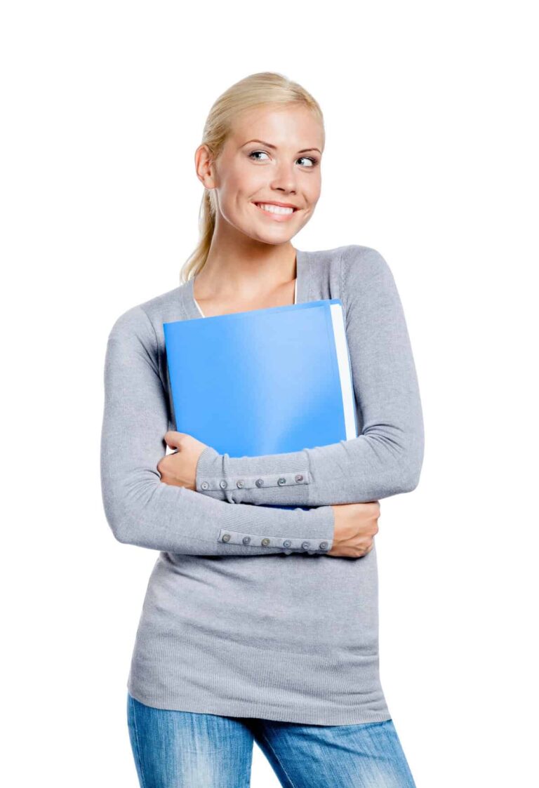 A person with blonde hair holds a blue folder, sporting a gray sweater and jeans, smiling and glancing to the side in a norep fashion.