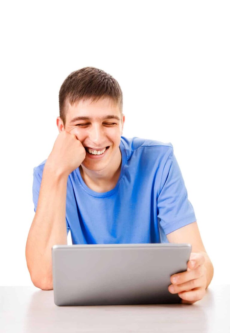 Young man with autism smiling while using a tablet computer.