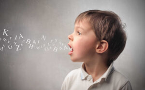 A young boy is blowing letters out of his mouth, demonstrating phonemic awareness.