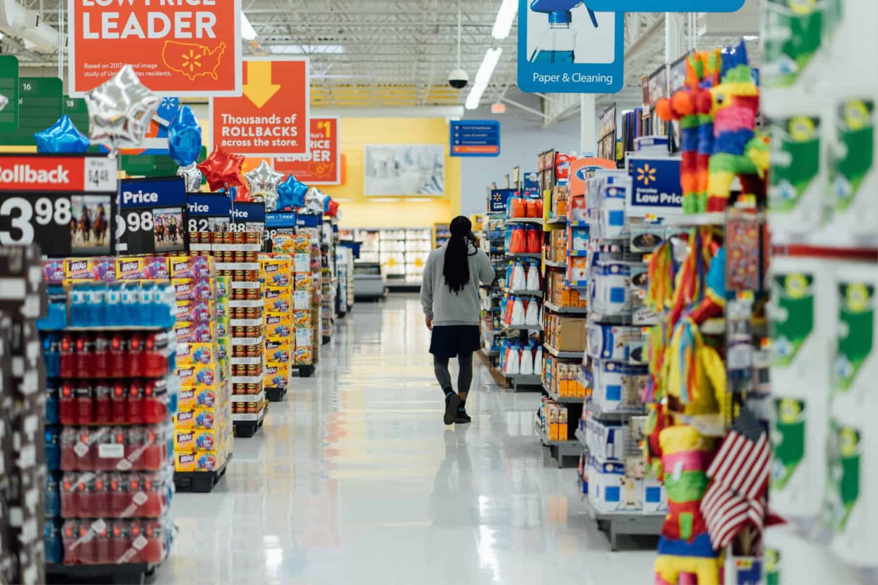 A person walks down an aisle in a supermarket with shelves stocked with various goods, practicing their independent functioning iep goals.