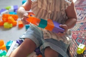A child sitting and playing with colorful interlocking plastic blocks, experiencing the difference floortime approach makes in engagement.