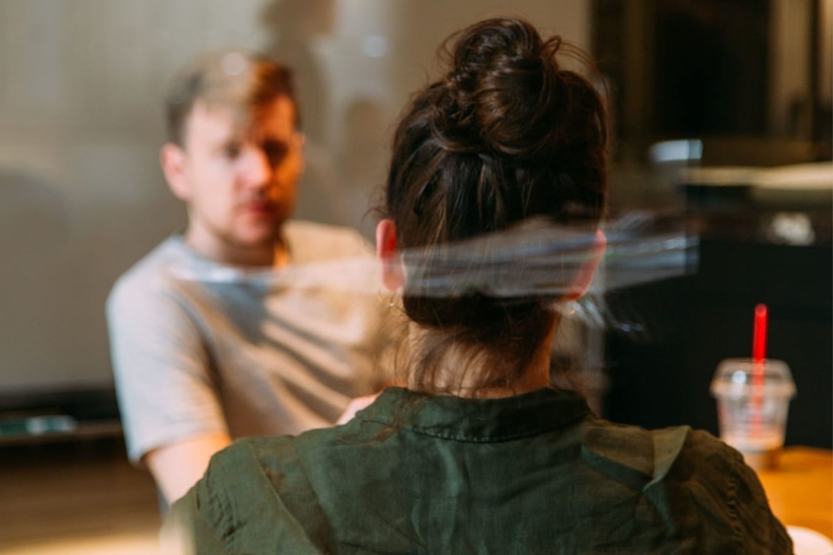 Two individuals in a casual setting focused on discussing vocational iep goals, with one facing the camera with her back, and the other slightly blurred in the background facing her.