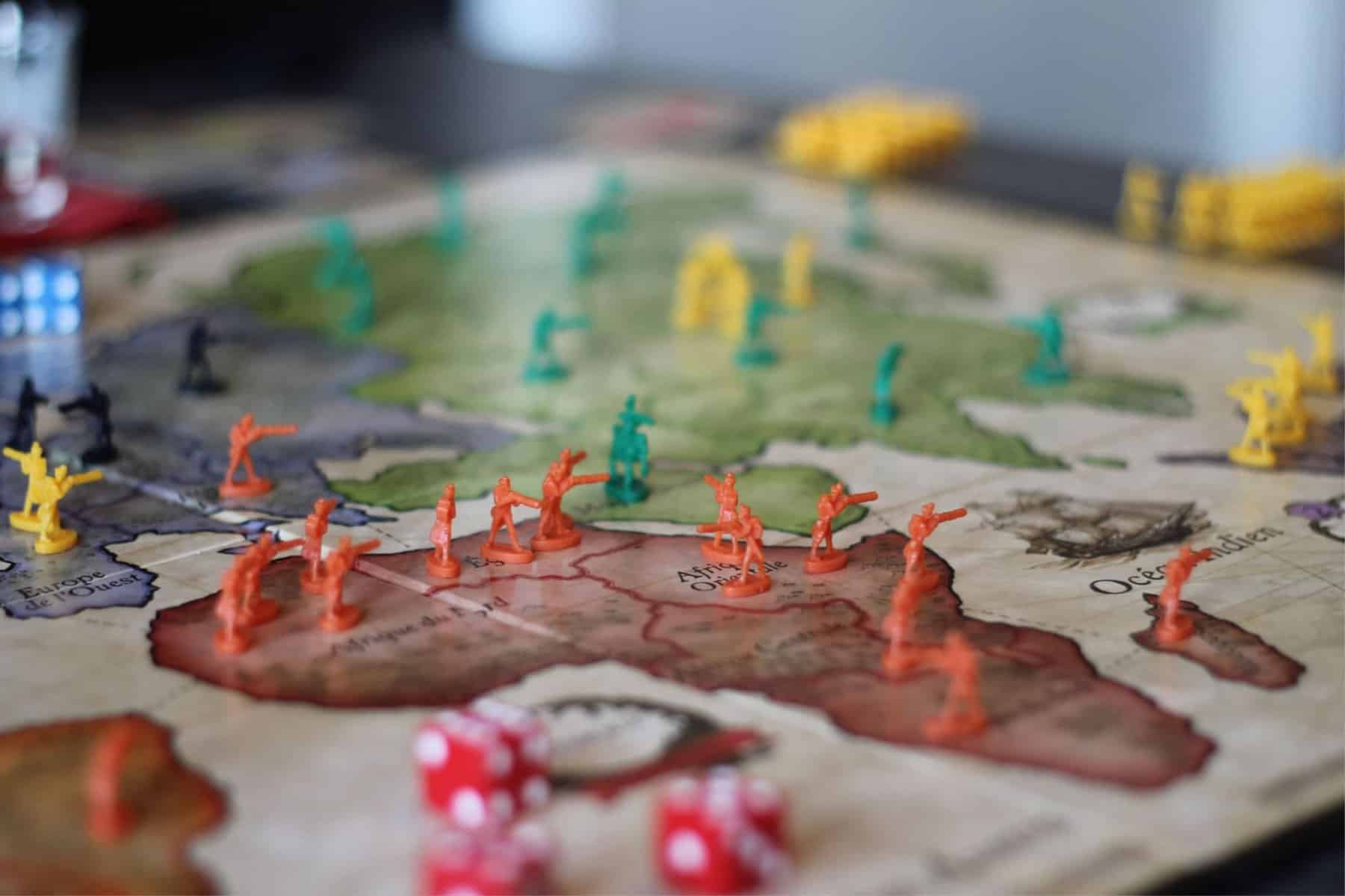 Close-up of a critical thinking risk board game with colorful miniature troops and dice.