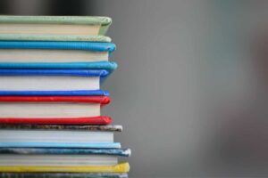 A stack of research-based hardcover books in various colors on a blurred background.