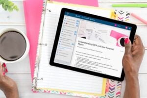 A person holds a tablet displaying a webpage titled "understanding idea and your parental rights," surrounded by an open notebook, papers, and a cup of coffee. This essential guide includes key iep questions and answers to help parents navigate their child's educational journey.