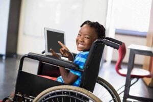 Student using a wheelchair and assistive communication device in a classroom setting as an example of 504 plan accommodations