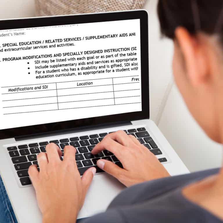 A person is using a laptop with an iep document open on the screen, concentrating on program modifications and reviewing sdi examples for iep in the specially designed instruction section.
