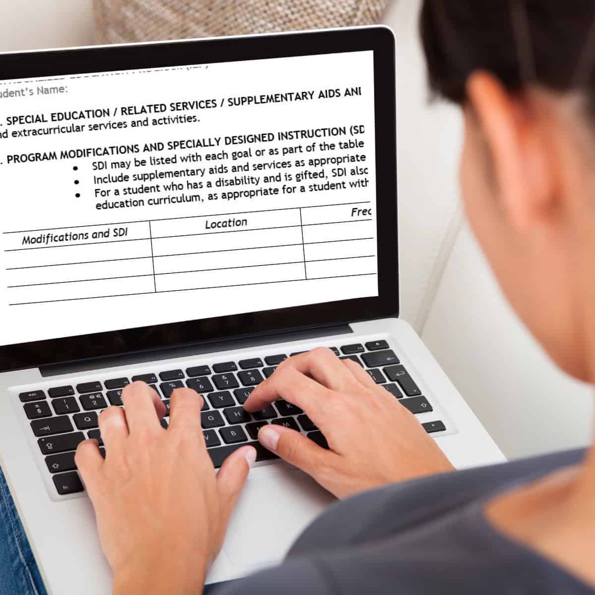 A person is using a laptop with an iep document open on the screen, concentrating on program modifications and reviewing sdi examples for iep in the specially designed instruction section.