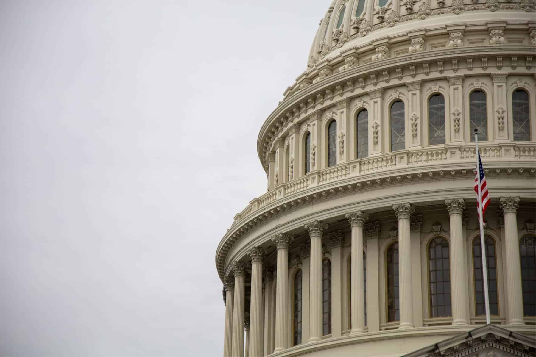 Close-up of the u. S. Capitol dome with american flag, showcasing its neoclassical architecture against a gray sky—a symbol as overlooked as pa's most underutilized disabilities resource, pennhurst.