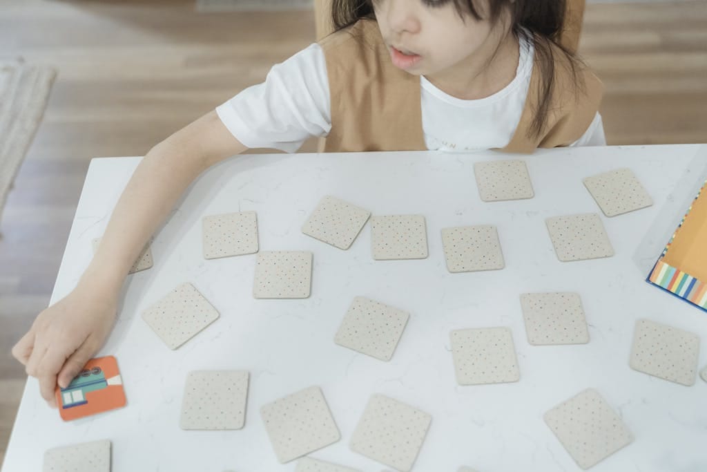 Young child playing a memory card game on a white table. High-angle view indoors.