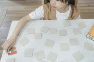 Young child playing a memory card game on a white table. High-angle view indoors.