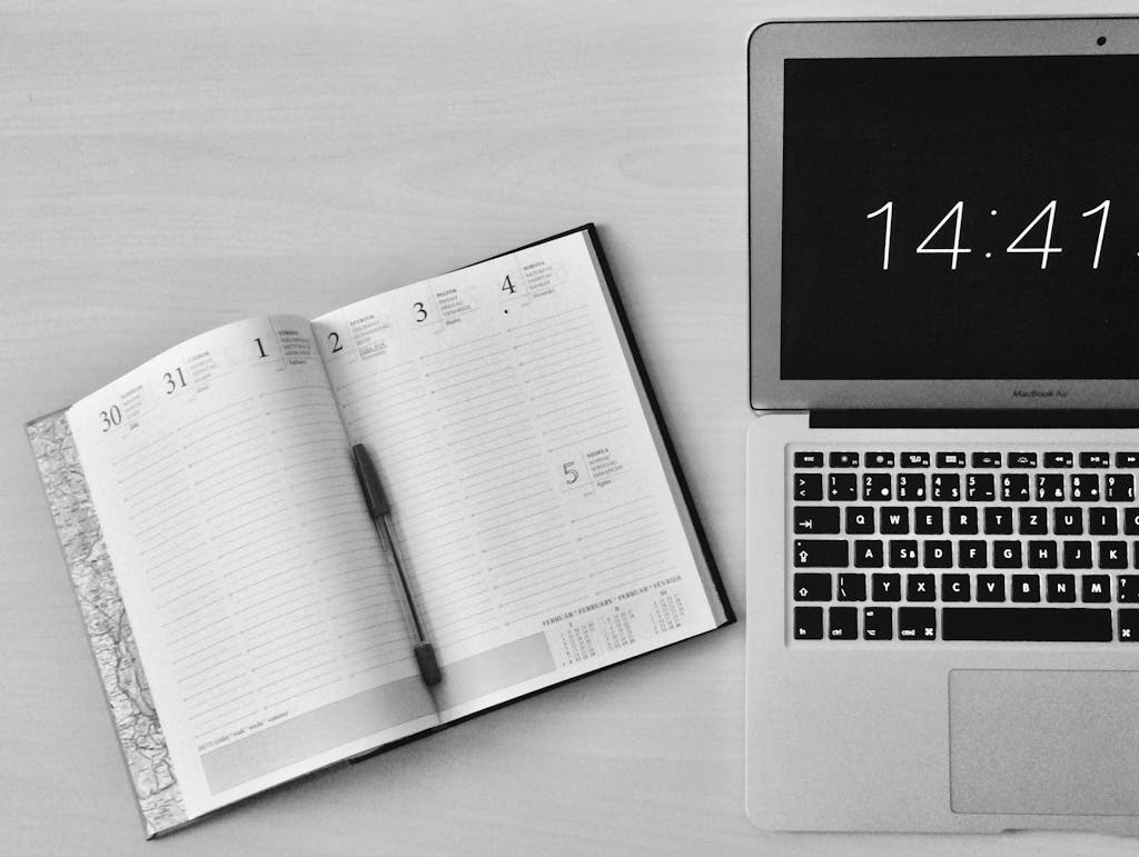 Minimalist office workspace with a notebook and macbook air showing 14:41 time.