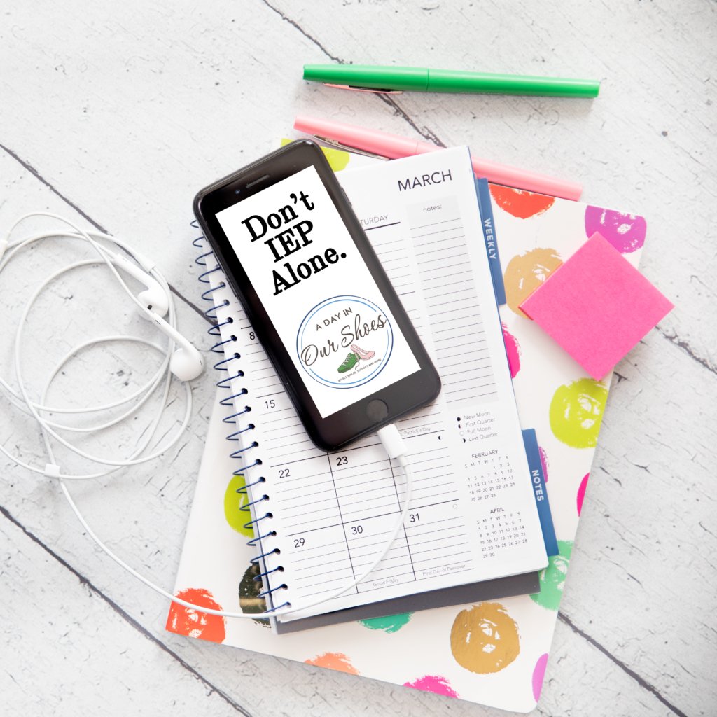 A smartphone with the message "don't iep alone" rests on a spiral planner, next to earphones, a green pen, and pink sticky notes—perfect essentials for teachers tracking professional development hours on a white wooden surface.