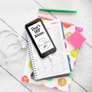 A smartphone with the message "don't iep alone" rests on a spiral planner, next to earphones, a green pen, and pink sticky notes—perfect essentials for teachers tracking professional development hours on a white wooden surface.