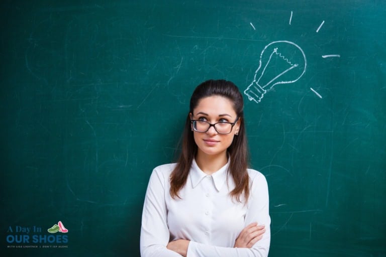 A woman in glasses stands in front of a chalkboard with a light bulb drawing above her head, suggesting she has an idea.