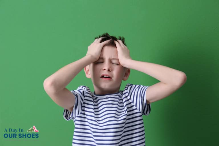 A boy in a striped shirt stands against a green background, holding his head with both hands and appearing distressed—possibly experiencing a fight or flight response. The logo "a day in our shoes" is visible in the corner.