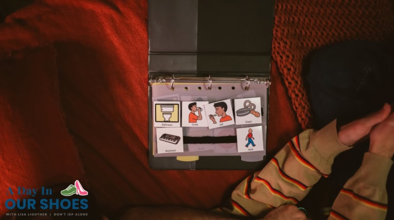A communication binder used in iep assessments for non-verbal students, with illustrated cards for "bathroom," "drink," "sock," "keyboard," and "walk," is open on a couch beside a person in a striped shirt.