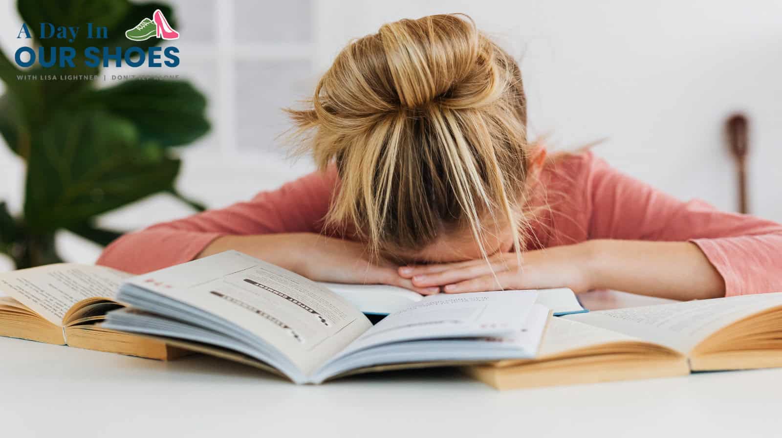 A person with blonde hair rests their head on an open book at a desk, surrounded by more open books, appearing tired or frustrated—suggesting procrastination or trouble starting tasks. Logo text is visible in the upper left corner.